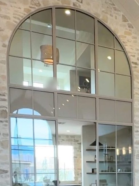 Arched steel-framed glass wall set into a stone accent wall beside the kitchen