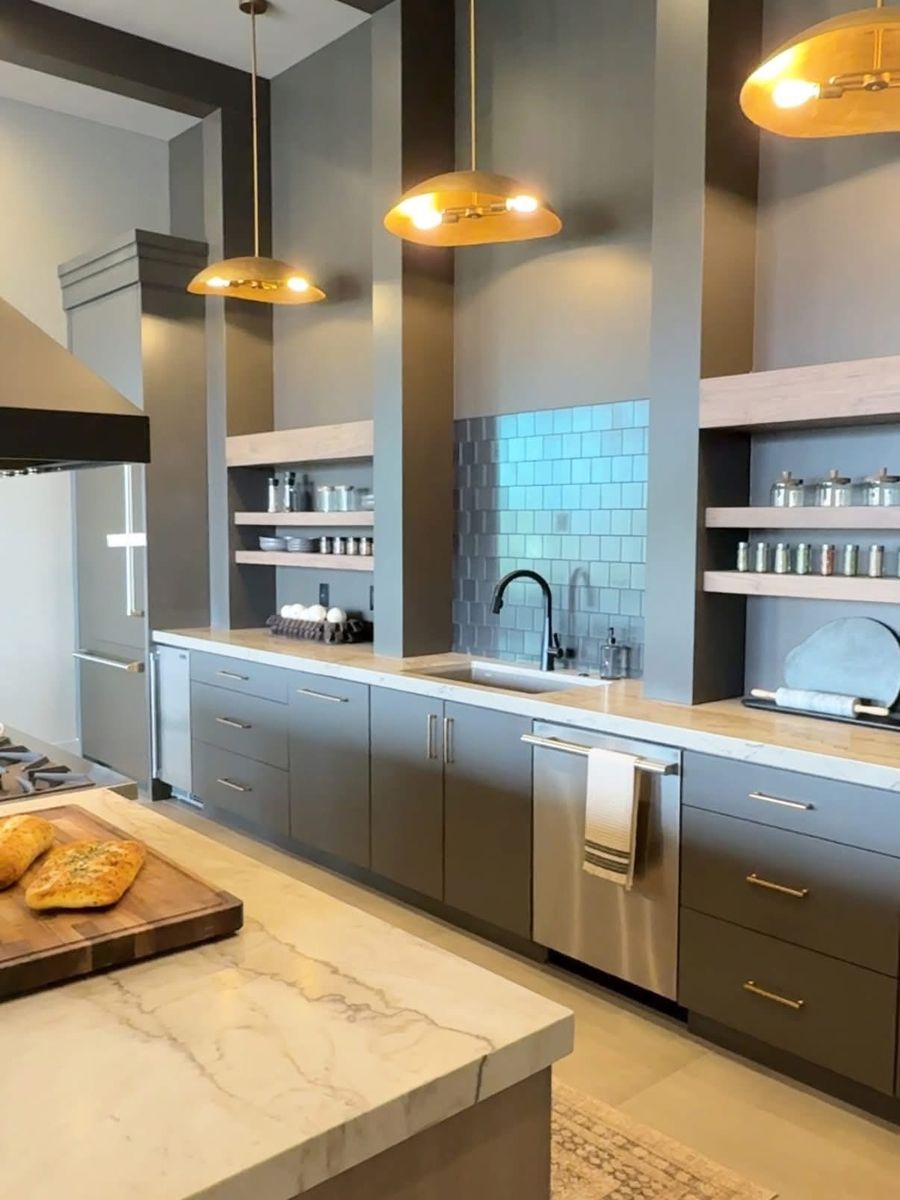 Kitchen with charcoal flat-panel cabinets, brass dome pendants, open shelving, a blue glass tile backsplash and a marble-look island