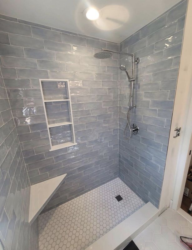 Shower with blue-gray subway tile, a built-in bench and a tiled shelf niche
